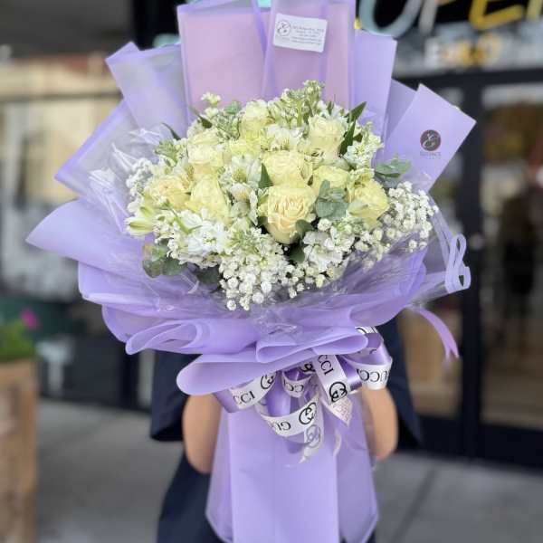 Lavender-wrapped bouquet of pale yellow and white flowers