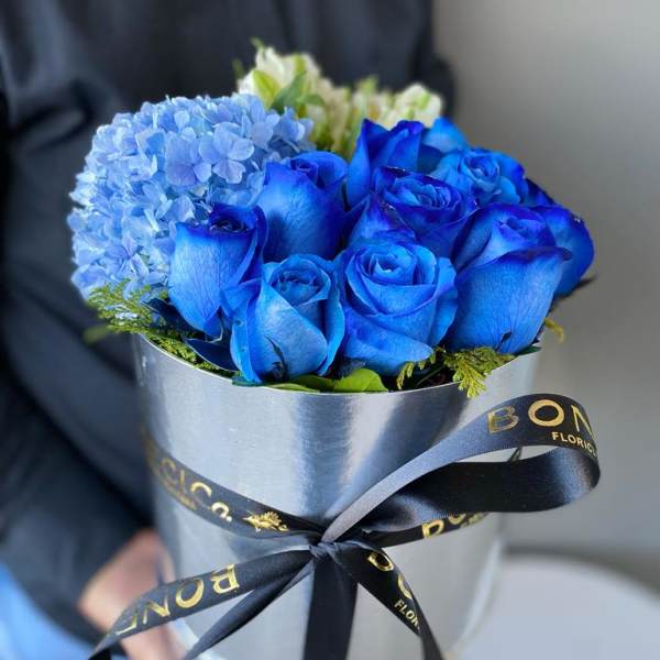 Blue roses and a blue hydrangea bouquet in a silver box with ribbon