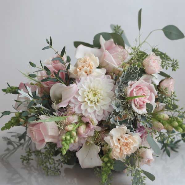 Soft pink and white bouquet with roses, calla lilies, and a central dahlia