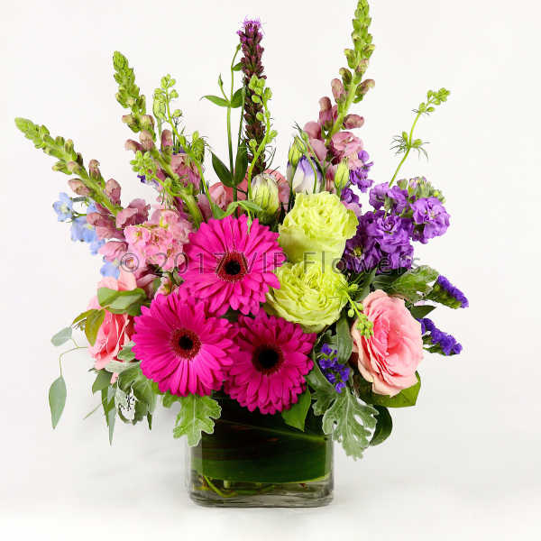 Bright mixed bouquet in a clear glass vase with pink and purple blooms
