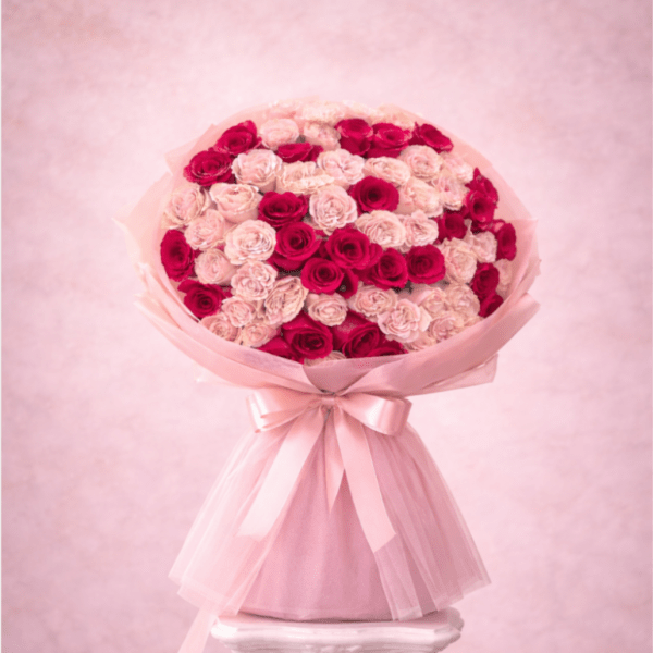 Large bouquet of pink and red roses wrapped in pale pink paper with a ribbon