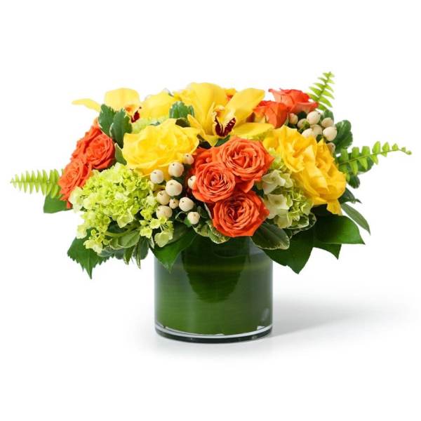 Low arrangement of yellow orchids and roses with orange roses in a green-lined glass cylinder vase