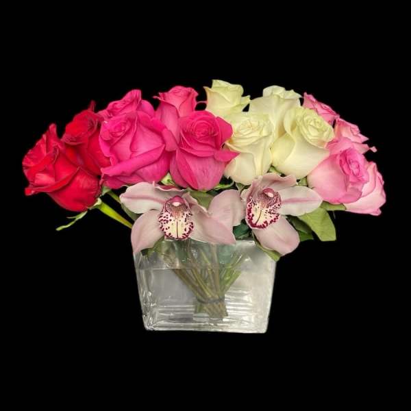 Low glass vase of red, pink, and white roses accented with two pale pink orchids in front.