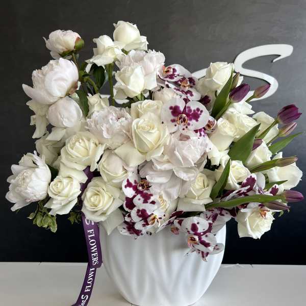 White floral arrangement with roses and orchids in a white vase