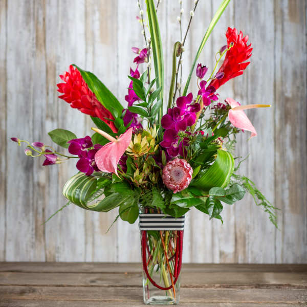 Tropical bouquet with pink orchids and red ginger in a glass vase