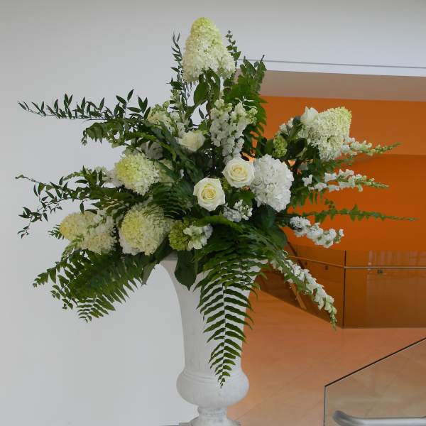 Tall white floral arrangement in a pedestal vase with roses and hydrangea