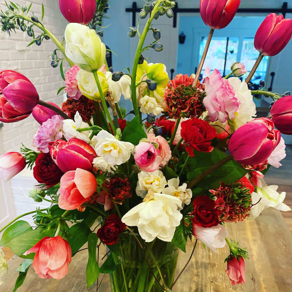 Mixed bouquet of pink, red, and white tulips in a clear glass vase