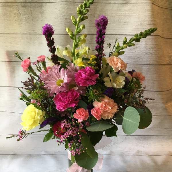 Mixed bouquet in a glass vase with pink, yellow, and peach flowers