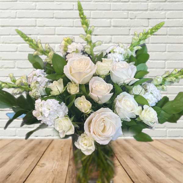 White roses and pale blooms arranged in a glass vase