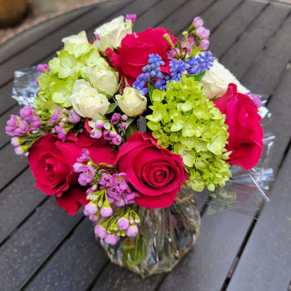 Bouquet of pink roses, white roses, and green hydrangeas in a glass vase