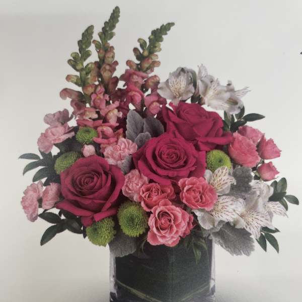 Pink and white mixed flower arrangement in a clear square vase