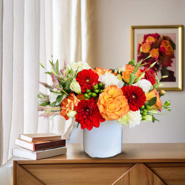 Bouquet of red, orange, and white flowers in a white vase