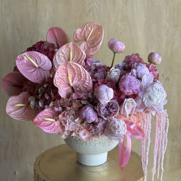 Pink floral arrangement in a white vase with anthuriums and peonies