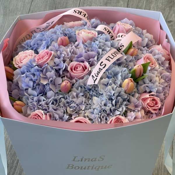 Bouquet of pink roses and blue hydrangeas in a gift box