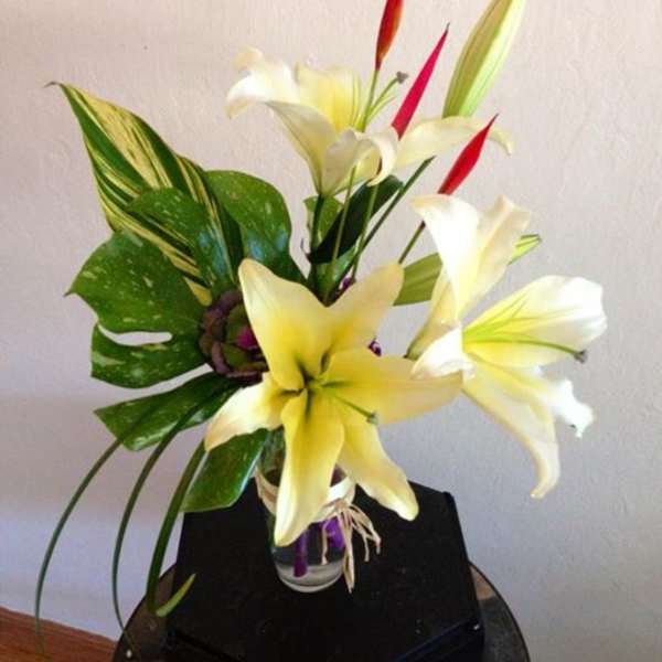 Arrangement of white and yellow lilies in a clear glass vase