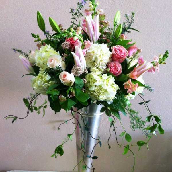 Tall floral arrangement in a silver pedestal vase with pink and white blooms