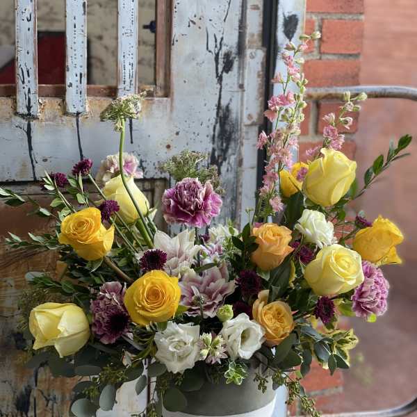 Mixed bouquet of yellow, white, and pink flowers in a round vase