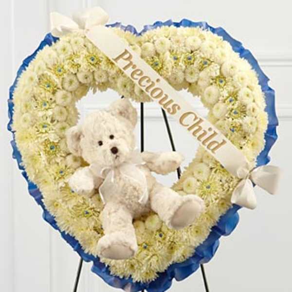 Heart-shaped white floral wreath with a teddy bear and ribbon banner