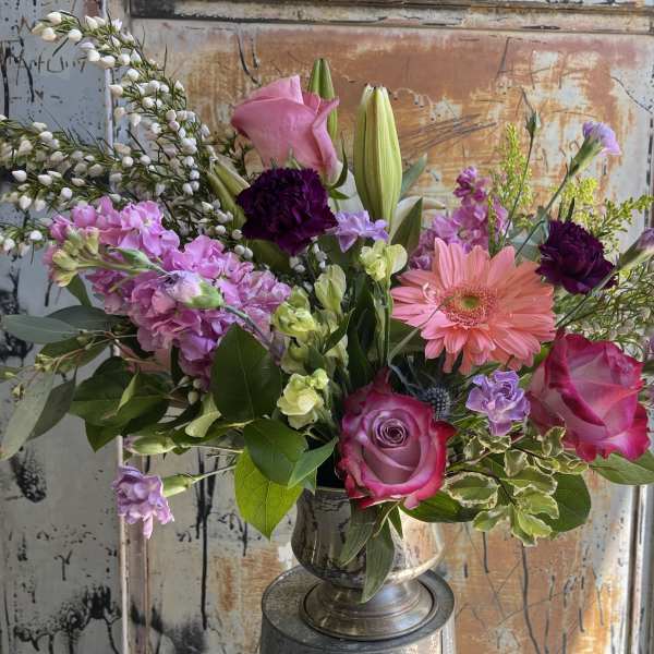 Mixed bouquet with pink roses, lilies, and a pink gerbera daisy in a silver vase