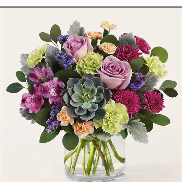 Mixed bouquet with roses, carnations, and a succulent in a glass vase