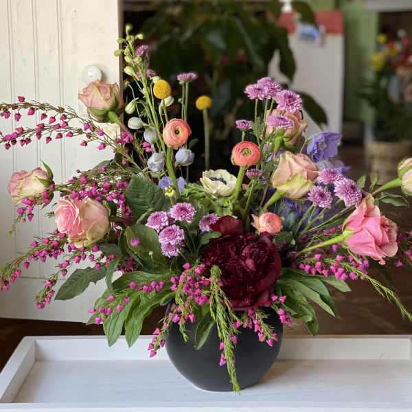 Mixed bouquet of pink, purple, and white flowers in a black vase