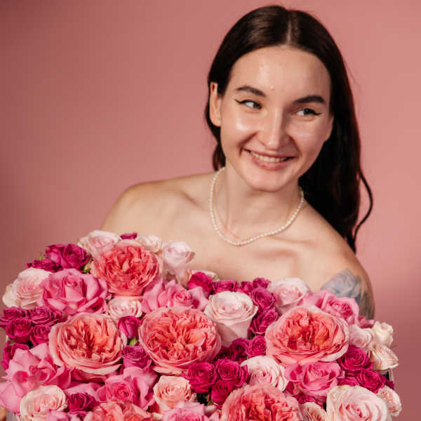 Woman holding a large pink rose bouquet in a box