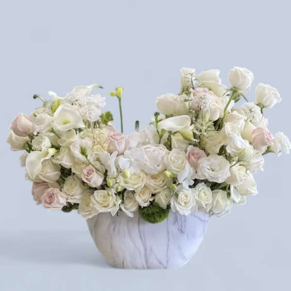 White and blush floral arrangement in a marble-patterned vase