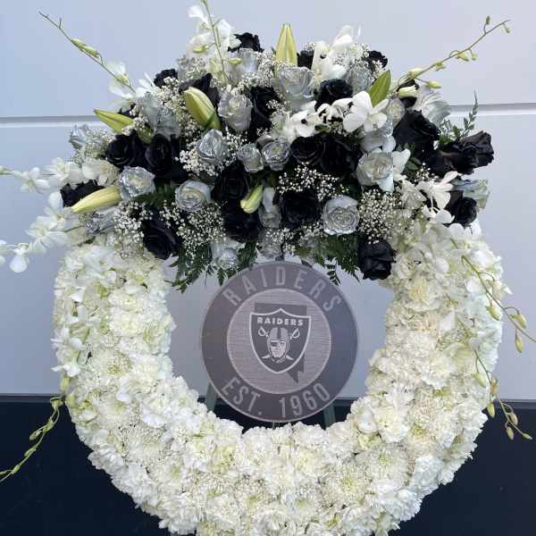 Large black, white, and silver floral wreath on an easel
