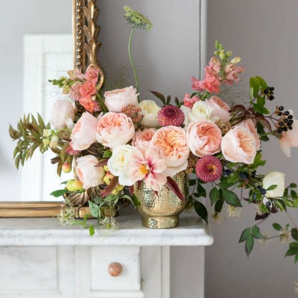 Blush and peach floral arrangement in a gold vase