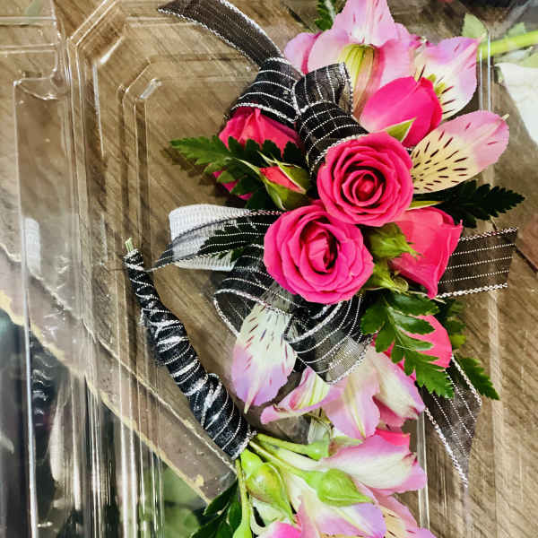 Pink roses and alstroemeria in a clear plastic box with black ribbon