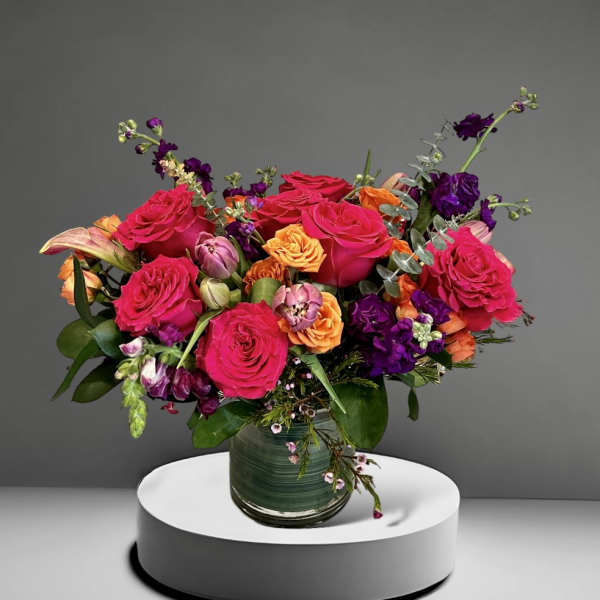 Bright mixed bouquet of roses and purple flowers in a glass vase