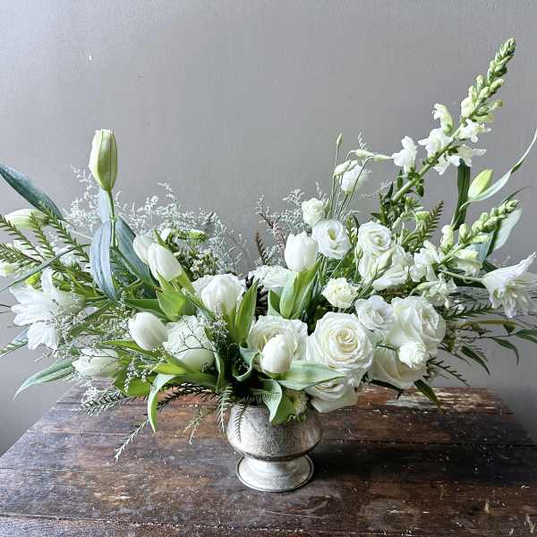 White floral arrangement in a silver vase with roses and tulips
