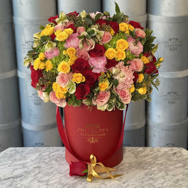 Mixed roses in a red hat box with a gold ribbon