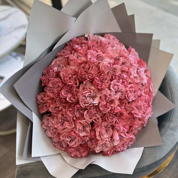 Large bouquet of pink roses wrapped in gray paper