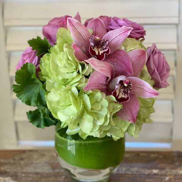 Pink orchids and green hydrangeas arranged in a glass vase