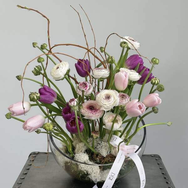 Mixed tulips and ranunculus in a clear glass bowl with a ribbon