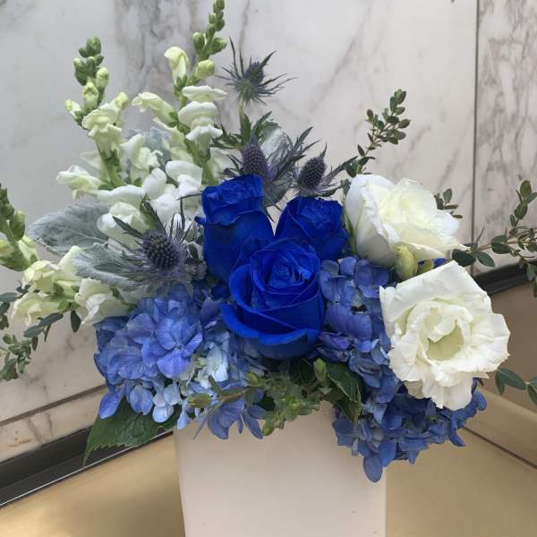 Blue and white floral arrangement in a white square vase