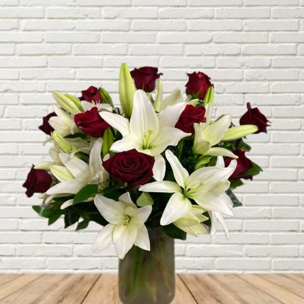 Bouquet of white lilies and deep red roses in a glass vase