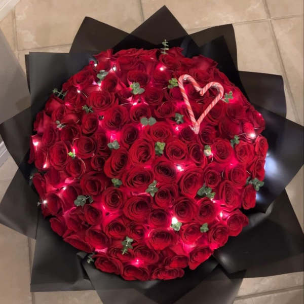 Large bouquet of red roses wrapped in black paper with a candy cane heart