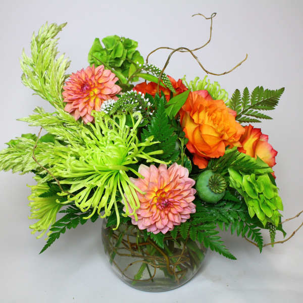 Bright mixed bouquet in a glass vase with orange, pink, and green blooms
