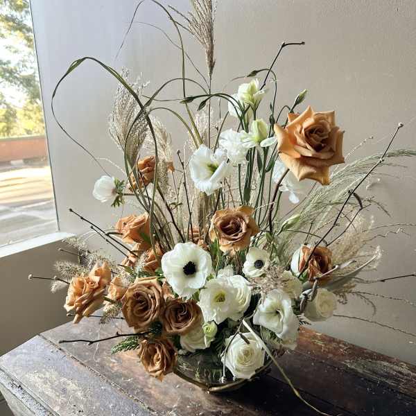 Arrangement of white and copper roses with white blooms in a low vase