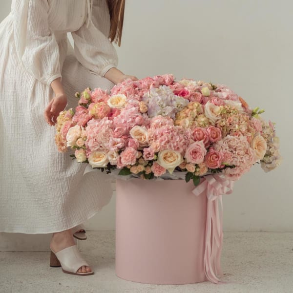 Large pink and cream floral arrangement in a round pink box