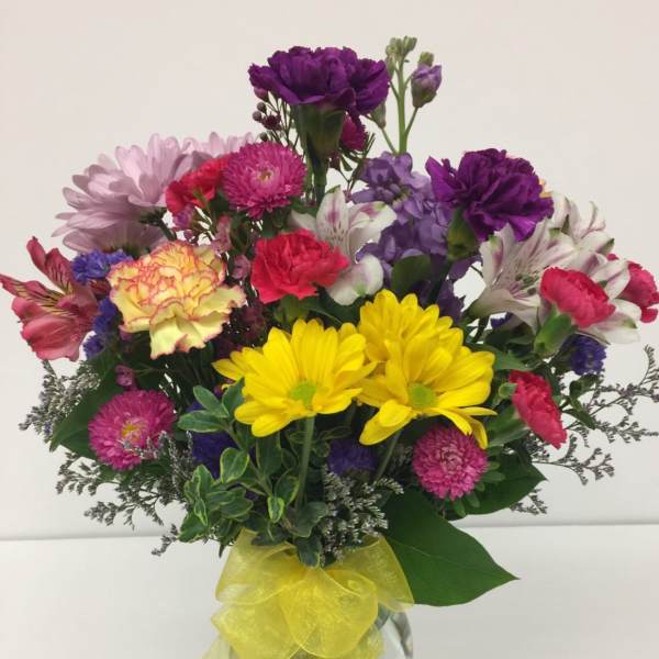 Colorful mixed bouquet in a glass vase with a yellow ribbon