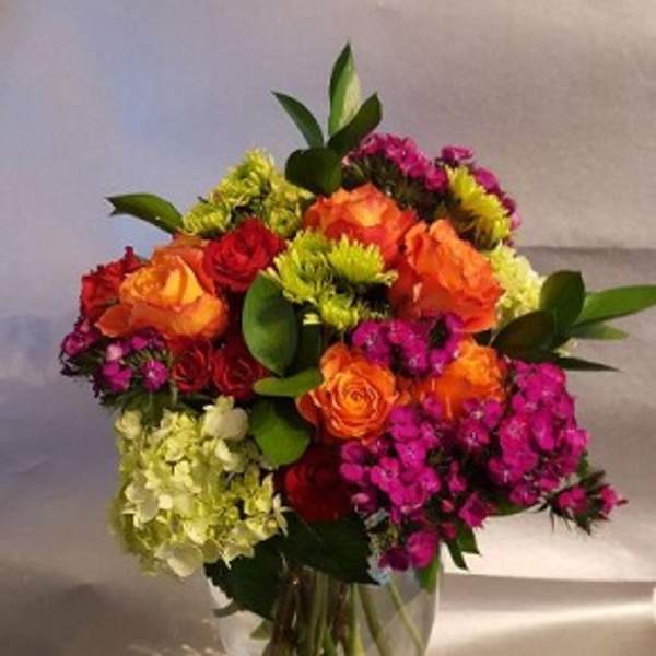 Colorful bouquet of roses and clustered blooms in a clear glass vase