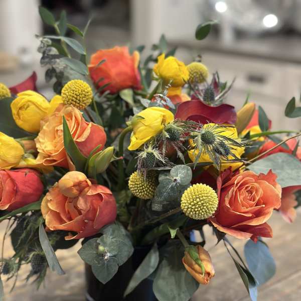 Orange and yellow rose bouquet in a black vase