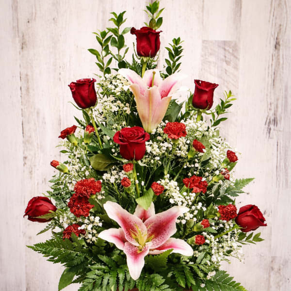 Red roses and pink lilies arranged in a wooden basket