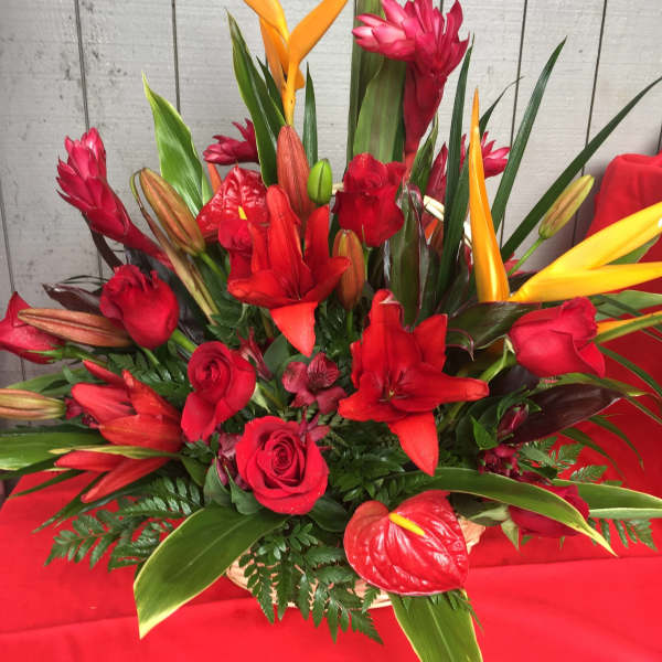 Red floral arrangement with orange tropical blooms and roses in a basket