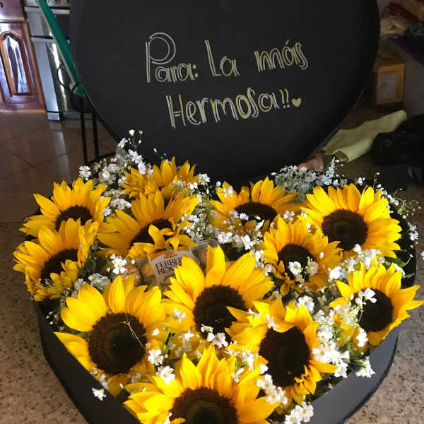 Heart-shaped box of sunflowers with a handwritten message on the lid