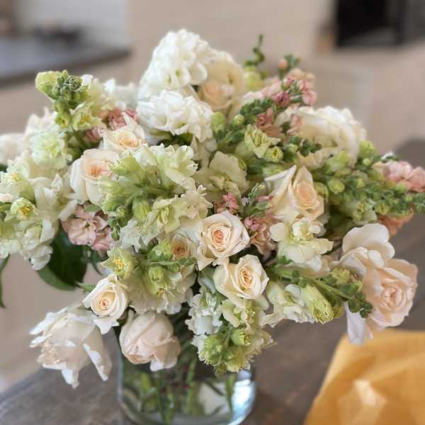 Bouquet of pale roses and white snapdragons in a glass vase