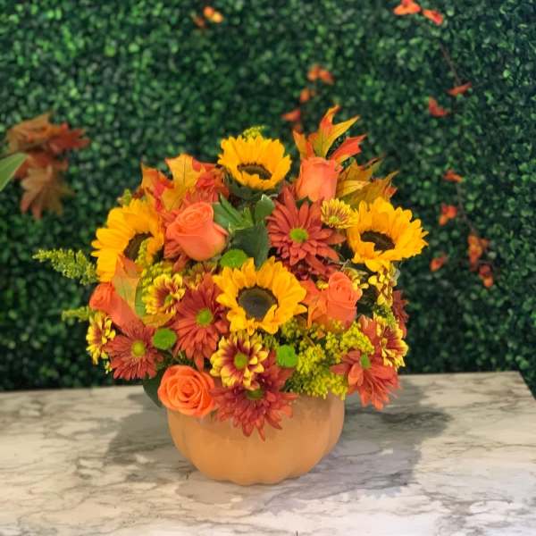 Autumn bouquet of sunflowers, roses, and mums in a pumpkin vase